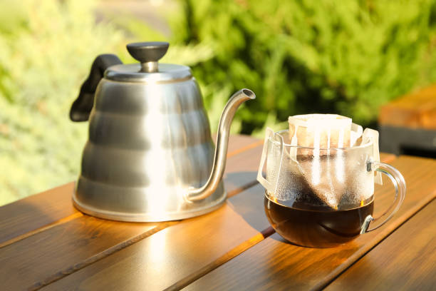 istock Glass cup with drip coffee bag and kettle on wooden table 1383826530