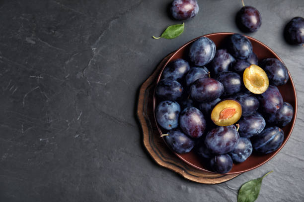 Delicious ripe plums on black table, flat lay. Space for text Delicious ripe plums on black table, flat lay. Space for text plum stock pictures, royalty-free photos & images