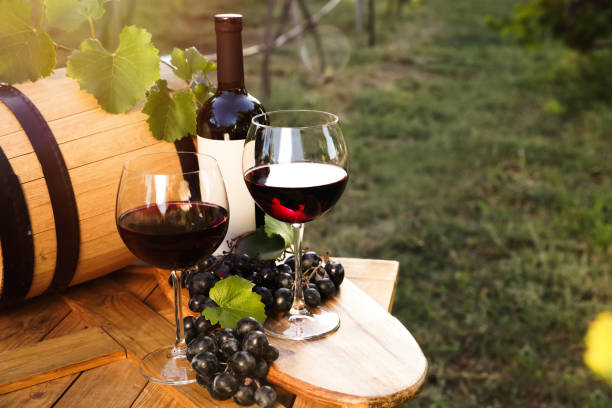 istock Composition with wine and ripe grapes on wooden table in vineyard 1383826684