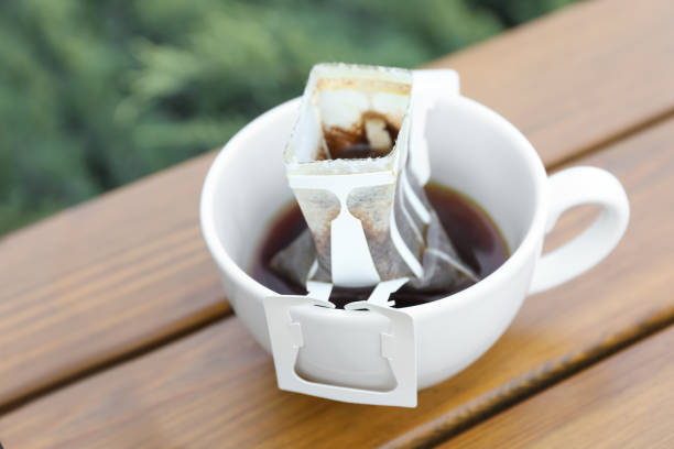 istock Cup with drip coffee bag on wooden table, closeup 1383827460