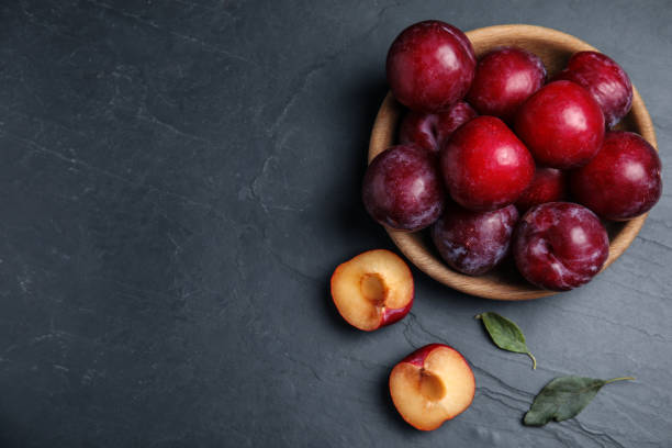 istock Delicious ripe plums on black table, flat lay. Space for text 1383827786