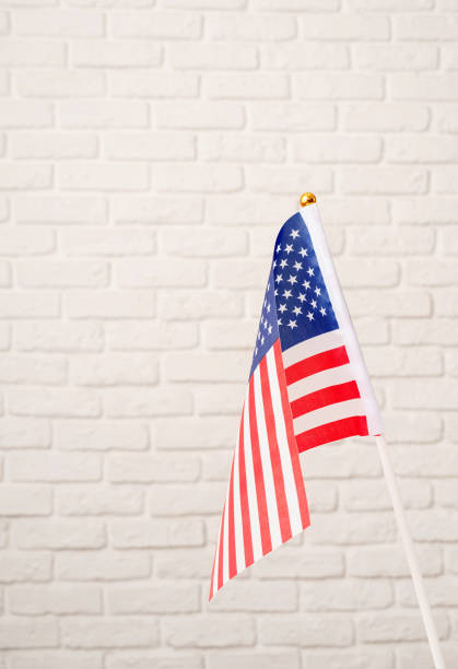 istock USA national flag on white brick wall background with copy space 1383828439