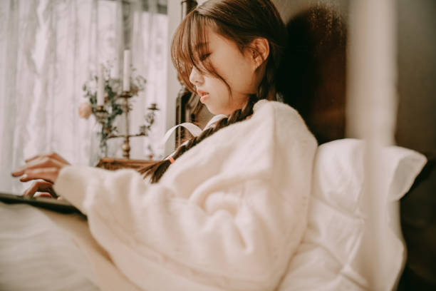 A beautiful asian girl reading in bed