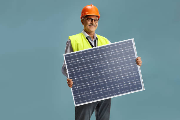 smiling male engineer holding a photovoltaic solar panel - order repairing telephone change imagens e fotografias de stock