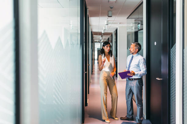 istock Business colleagues interacting with each other while walking in the corridor at office 1383833288