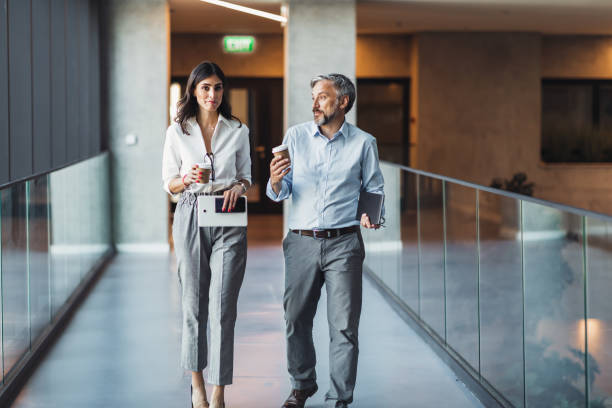 istock Business colleagues interacting with each other while walking in the corridor at office 1383833391