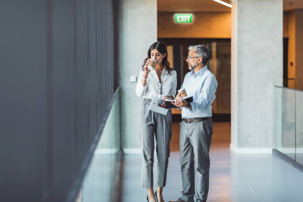 istock Business colleagues interacting with each other while walking in the corridor at office 1383833400
