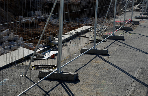 Construction sites with portable fence parts that are installed in plastic weight racks hold the stability of the fencing. along the sidewalk made of interlocking paving