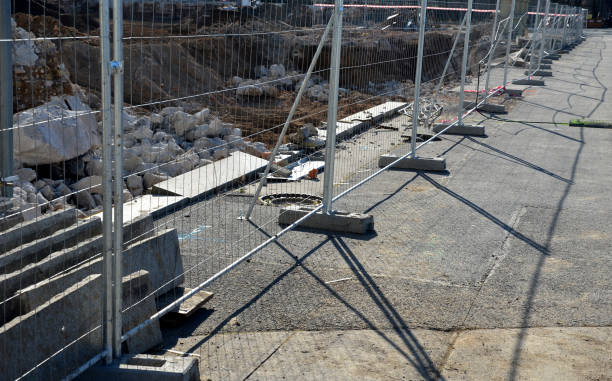 Construction sites with portable fence parts that are installed in plastic weight racks hold the stability of the fencing. along the sidewalk made of interlocking paving Construction sites with portable fence parts that are installed in plastic weight racks hold the stability of the fencing. along the sidewalk made of interlocking paving temporary stock pictures, royalty-free photos & images