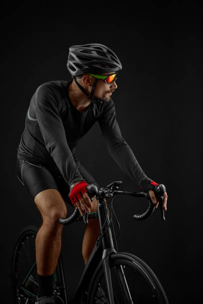 istock male cyclist riding road bicycle on black background 1383835011