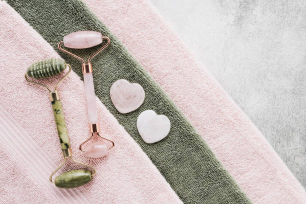 istock Face Massage tools. Gua Sha massages and jade facial rollers on a pink towel. SPA concept 1383835486