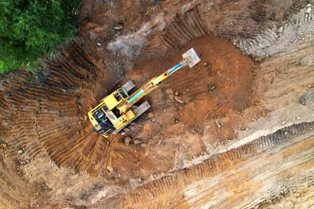 Excavator on earthmoving at construction site. Excavator on earthworks. Open pit development and sand mining. Loader digg ground, top view. Earthmover and digger on groundwork.