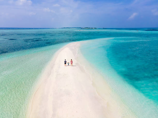 familie mit kleinkind am schönen strand verbringen urlaub auf der tropischen insel mit weißem sand, türkisfarbenem meerwasser und blauem himmel. paar mit kleinem kind, das zusammen geht. - beach men isolated tourist stock-fotos und bilder