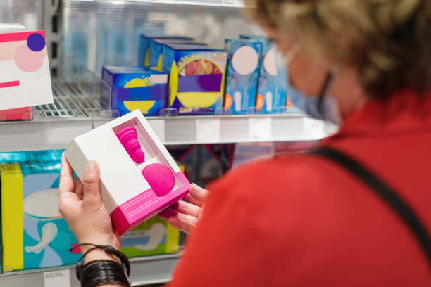 mulher escolhendo produto sanitário, segurando uma caixa de copo menstrual em supermercado - tampon healthcare and medicine menstruation indoors - fotografias e filmes do acervo