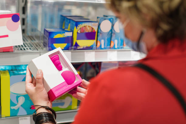 женщина выбирает санитарное средство, держа коробку менструальной чаши в супермаркете - tampon healthcare and medicine menstruation indoors стоковые фото и изображения