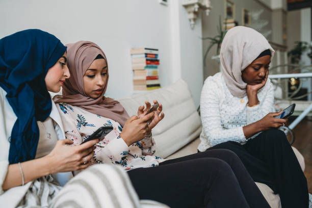 istock Arab friends using mobile phones sitting on the sofa at home 1383842633