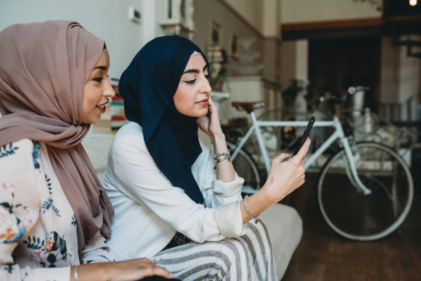 istock Arab friends using mobile phones sitting on the sofa at home 1383842637