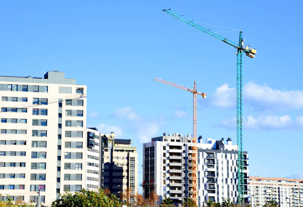 Tower crane on the construction of a residential building. Construction site with cranes for building construction. Tower cranes in action. Housing renovation and Real Estate concept.
