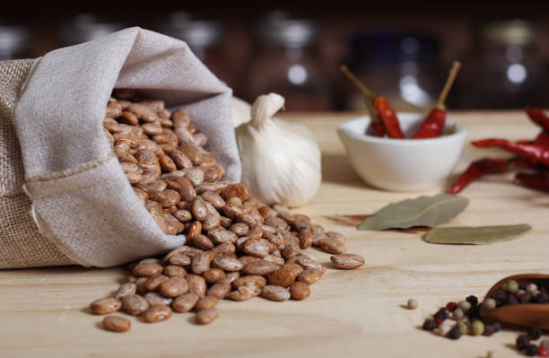 Burlap Sack of Pinto Beans on Table with Spices in Background stock photo