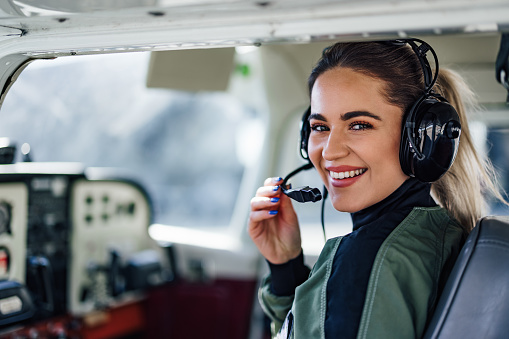 Confident female plane captain, ajusting her microphone, prepari