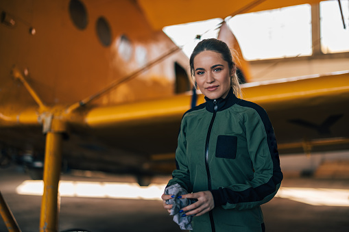 Retrato de una piloto confiada en el traje, de pie junto a un avión. photo