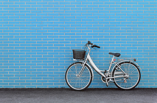 Women's bicycle against a turquoise brick wall