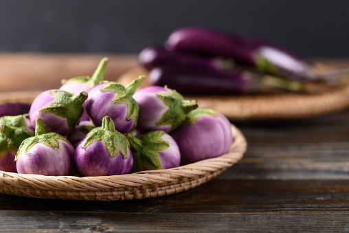 Thai purple eggplant in small basket on wooden background, Food ingredient