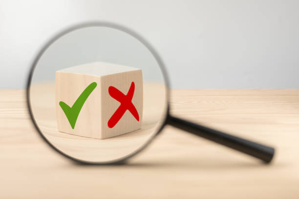 analyze pros and cons. magnifying glass with green tick and red cross in focus on wooden cube. consider all arguments pros and cons. choices tick yes or no choose mark decision - age contrast imagens e fotografias de stock