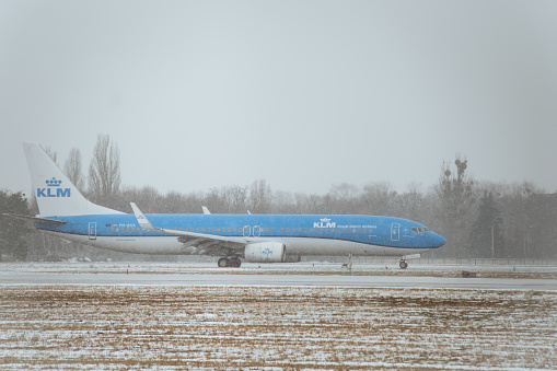 KYIV, UKRAINE - FEBRUARY 03: KLM airlines aircraft taxiing after landing in Boryspil international airport.  Modern passenger airplane with white and blue livery on the runway during shower snow.