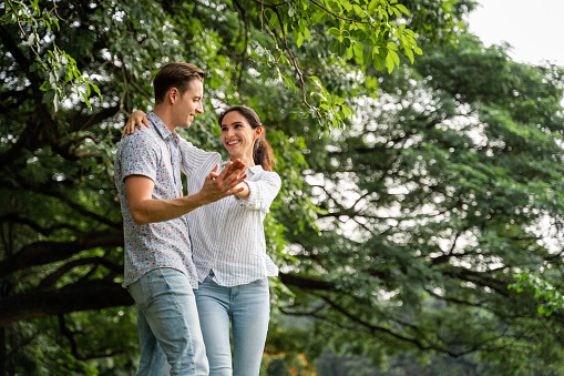 Young couple having fun in the moment of love in the park. Love and tenderness, Romantic man playing guitar to his girlfriend, lifestyle concept