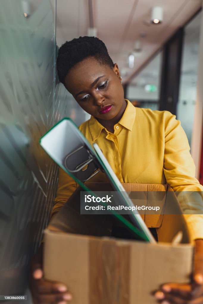 Fired businesswoman packed his bags and leaving office. The young black woman was stressed and disappointed by being fired. concept of layoffs and unemployment. Being Fired Stock Photo