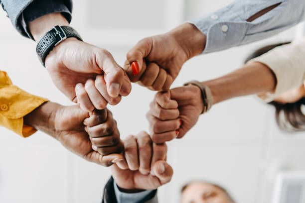 Cropped top above high angle view of three elegant stylish sales managers putting fists togetherCloseup of a group of businesspeople joining their hands together. Team concept, circle of fist bump assemble together, view from below, copy space team harmony stock pictures, royalty-free photos & images