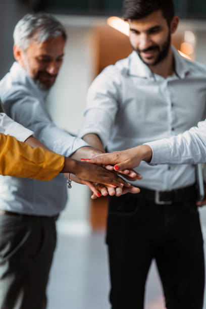 istock Close up mixed race business people putting hands together, support and unity concept. Diverse colleagues joining in team building activity, staff training concept, start working together, teamwork. 1383860703