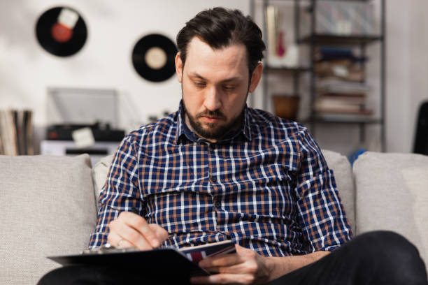 istock A final year student is preparing for an English exam. A middle-aged man with a beard is sitting on a couch with an English dictionary in his hands 1383862958