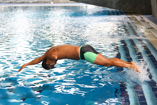 An Asian man with amputated left arm is enjoying swimming at swimming pool.