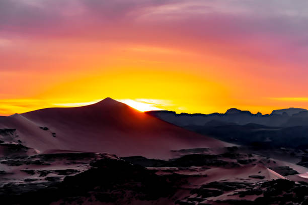 Colorful sunset behind a huge sand dune landscape.