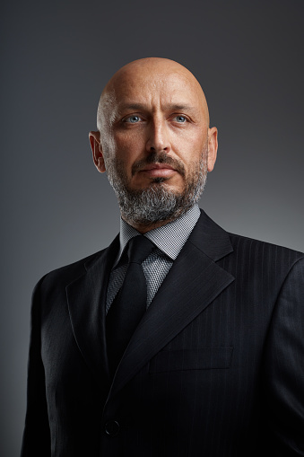 Studio portrait of a middle eastern middle-aged bearded businessman posing against a dark background