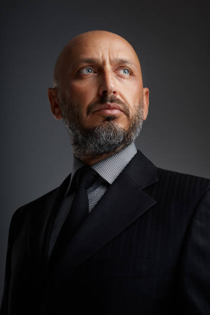 Studio portrait of a middle eastern middle-aged bearded businessman posing against a dark background