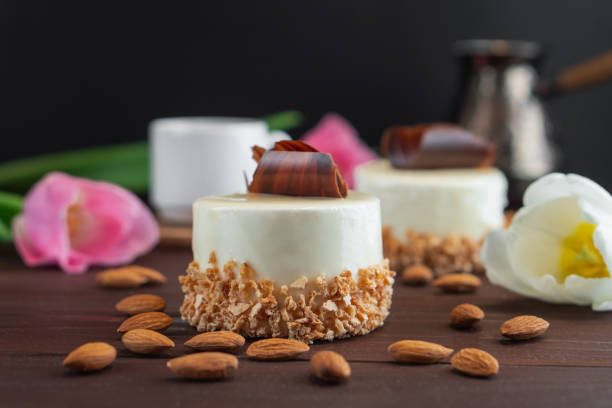 Two cupcakes with chocolate white coffee cup almond and tulips on wooden table. Selective focus