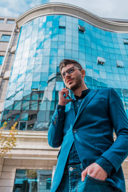 istock Urban businessman in blue suit coat talking on mobile 1383868728