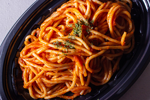 Closeup takeout Japanese Naporitan Spaghetti in the food tray. Naporitan (or Napolitan) is a popular Japanese style pasta dish. The dish consists of spaghetti, tomato ketchup or a tomato-based sauce