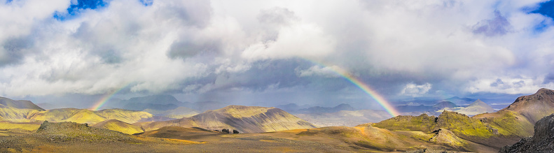 Rainbow in the sky over the colourful mountains around the Landmannalaugar area in Iceland during summer in the Fjallabak Nature Reserve in the Highlands of Iceland. Wide panoramic landscape photo.