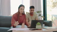 istock 4k video footage of a young couple sitting together and using a laptop to calculate their finances 1383880410