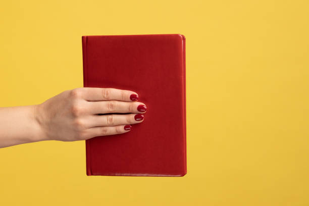 istock Woman hand holding showing red book with interesting plot, studying with pleasure. 1383881321