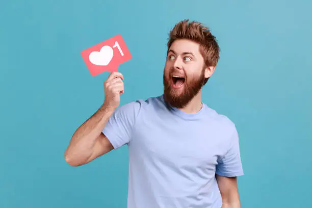 Photo of Man in T-shirt holding like counter sign asking for more reactions on his content in social media.