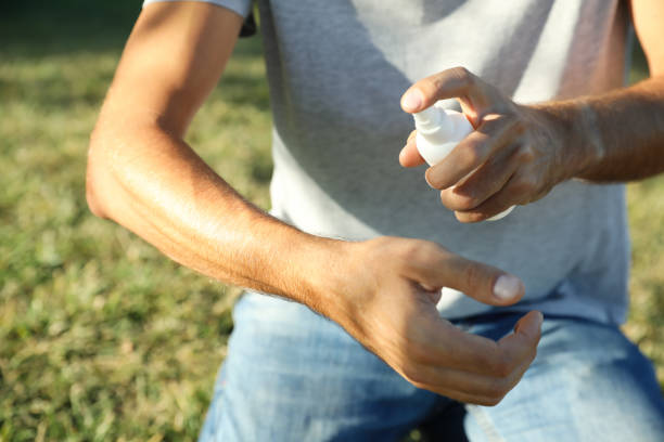 istock Man applying insect repellent onto arm outdoors, closeup 1383882735