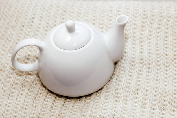 Teapot with tea on the background of natural warm knitted fabric pattern