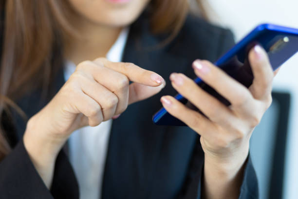 istock Woman holding a mobile phone using her finger to press the unlock code. 1383886810