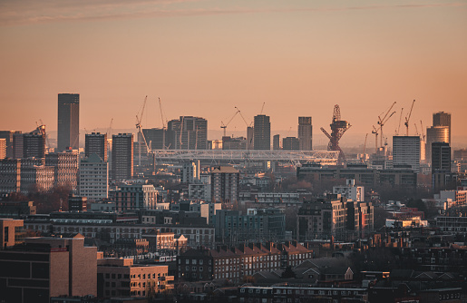 Aerial panoramic view of East London cityscape skyline with metropole Stratford, Westfield and Olympic Stadium after sunset with illuminated buildings and cloudy sky in London, UK