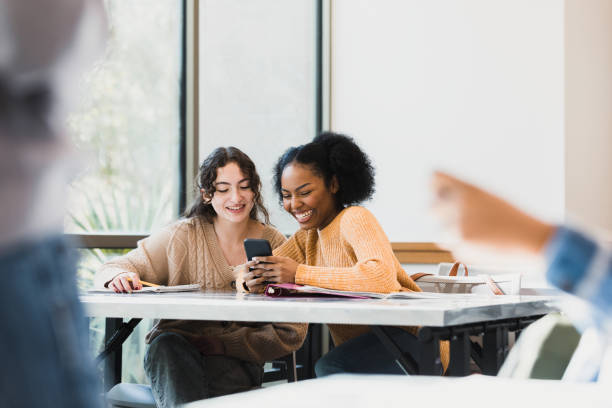 istock Female classmates look at phone 1383890696